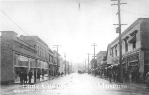 View of Main Street in Cottage Grove, Oregon. The Burkholder Woods building is visible on the left and the Woodward Building is visible on the right.